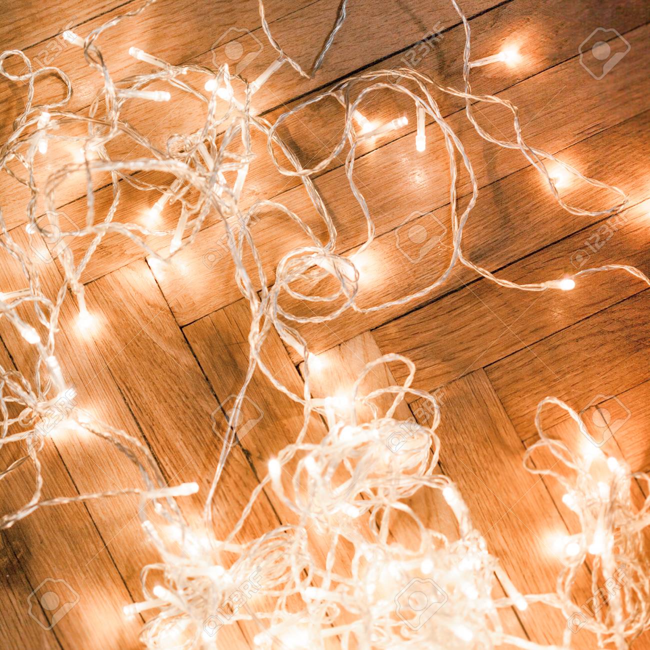 Christmas background with festive decoration - Christmas glowing lights garland on a old antique wooden parquet floor, sparkling garland for greeting card. Christmas background with festive decoration